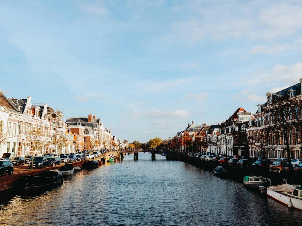 A scenic view of a Dutch canal flanked by historic buildings and boats in daylight.